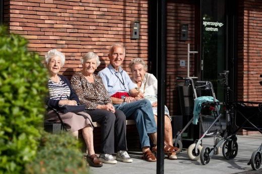 Ouderen genieten van de zon op een bankje aan het dagverzorgingscentrum van de Refuge in Gent