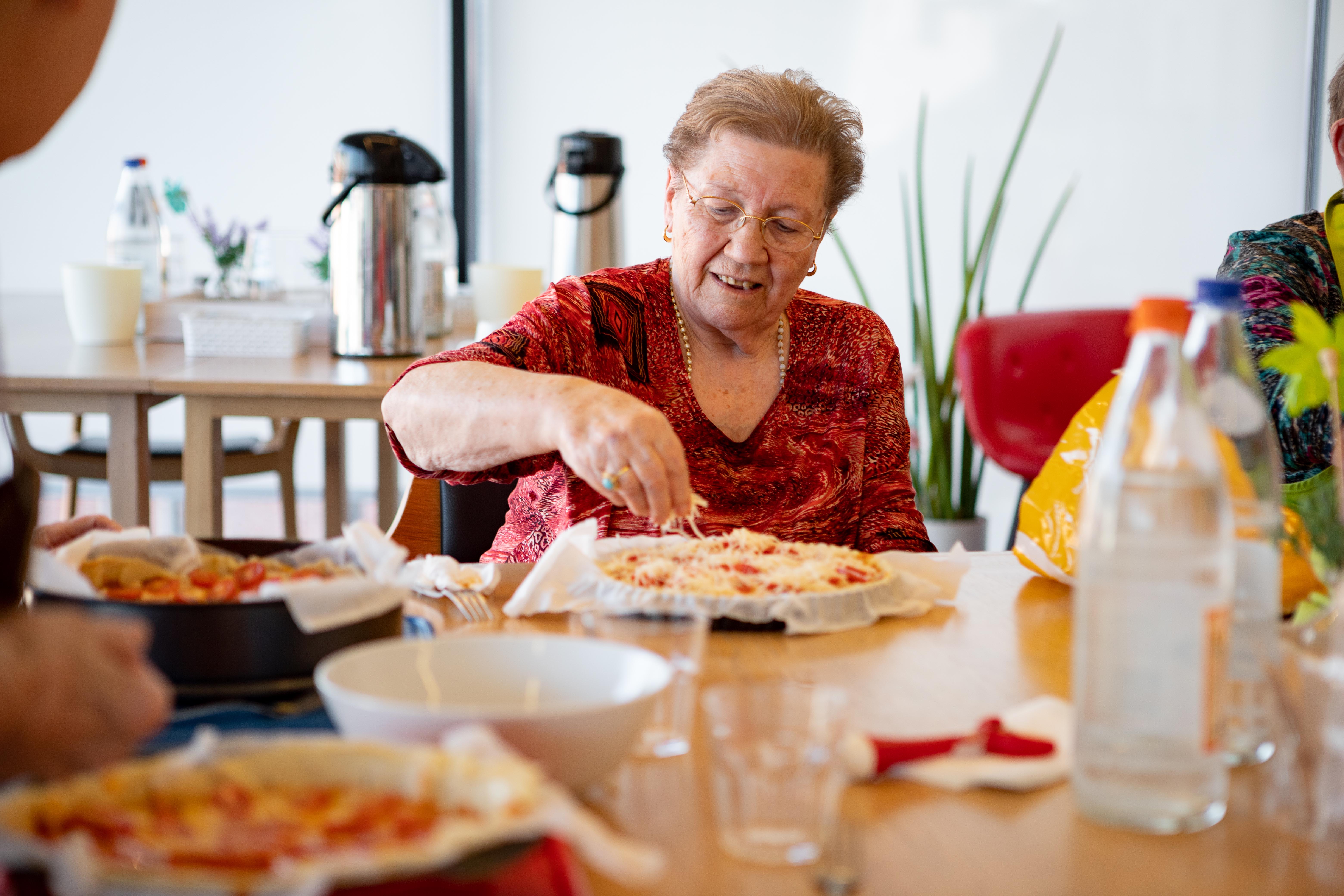 Oudere dame neemt deel aan de middagactiviteit pizzas maken in de Refuge Gent