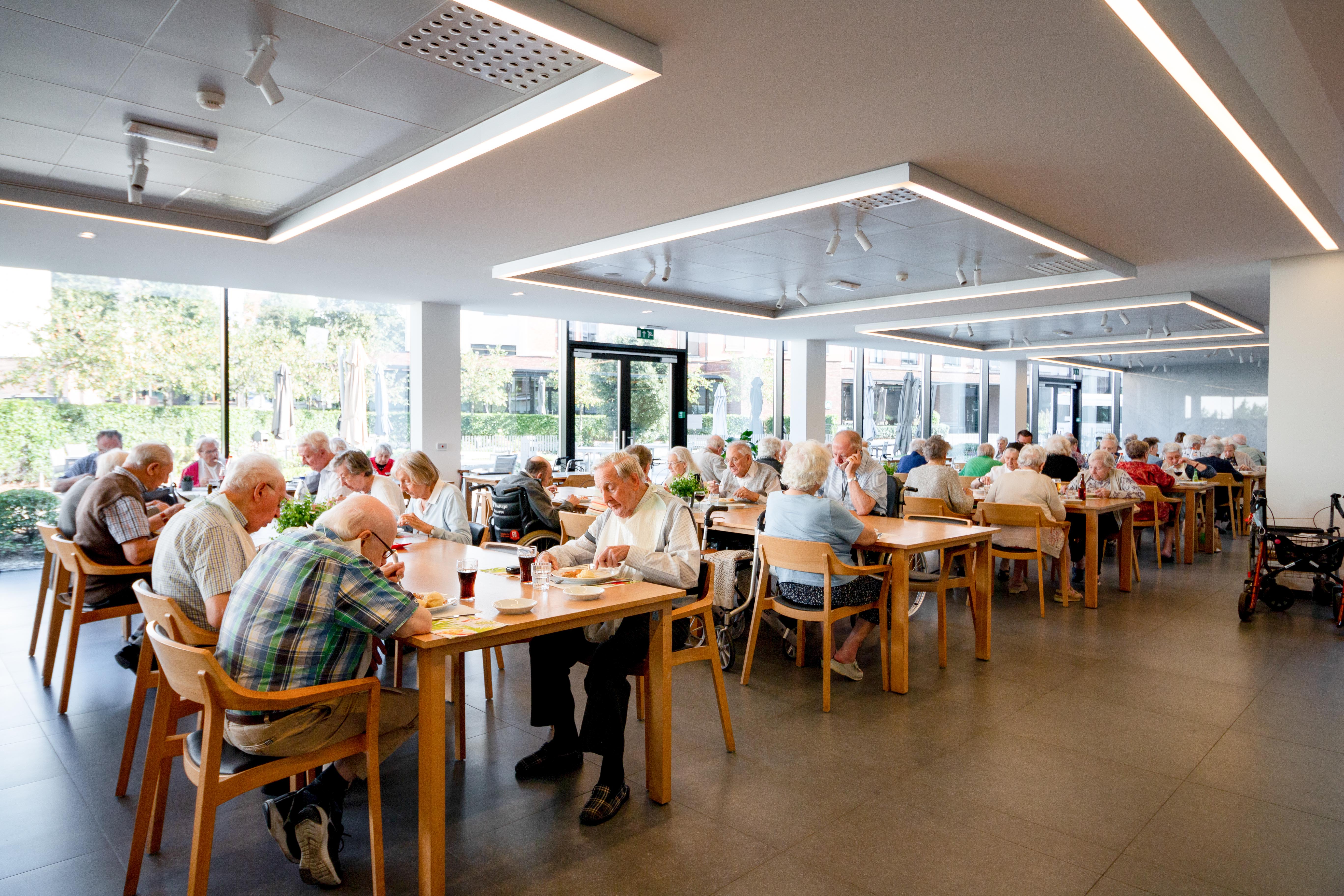Ouderen genieten van het middagmaal in het restaurant en Grand Café in De Refuge in Gent