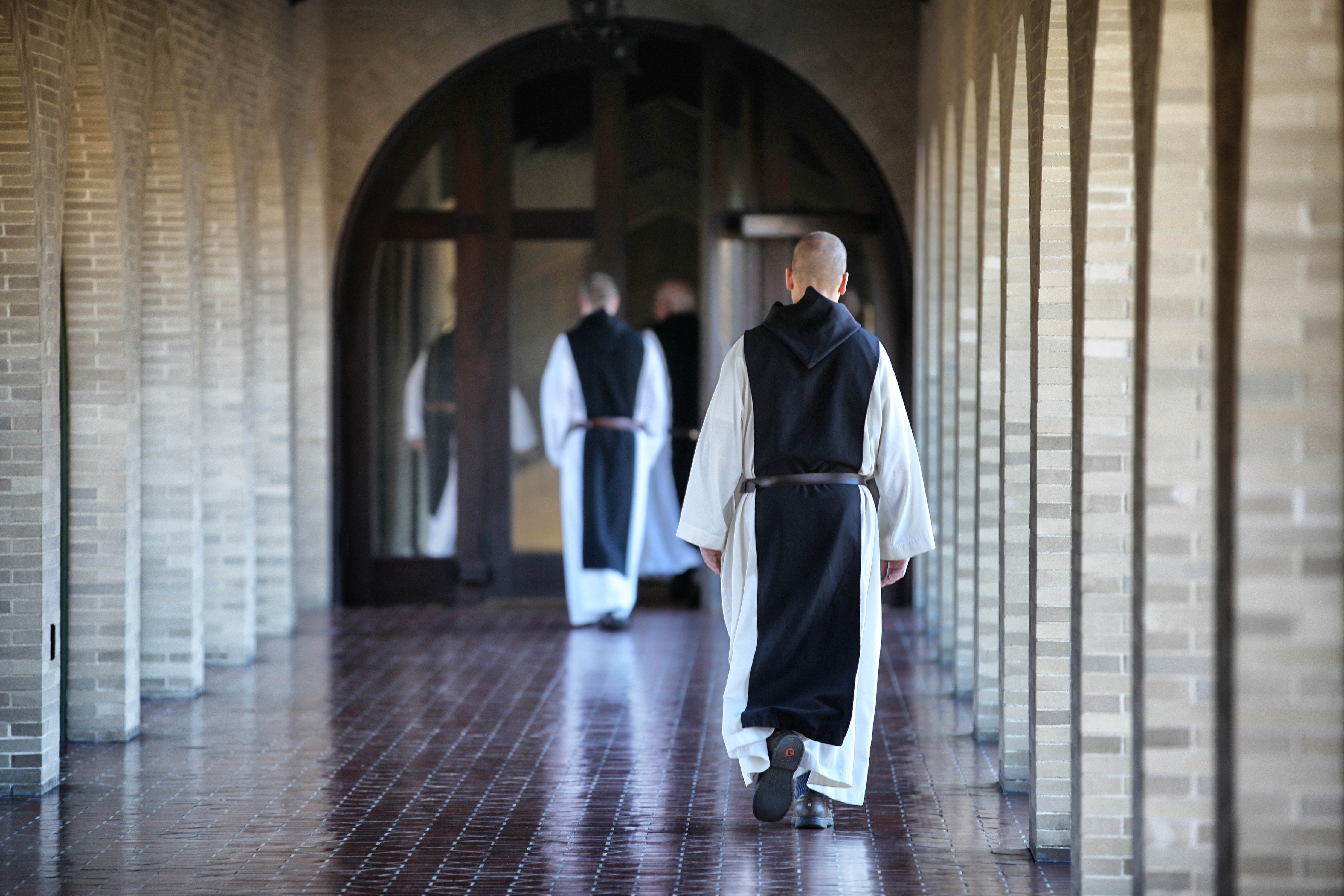 Paters in habijt in de kloostergang
