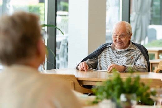 Blije senior man in het restaurant van de Refuge in Gent