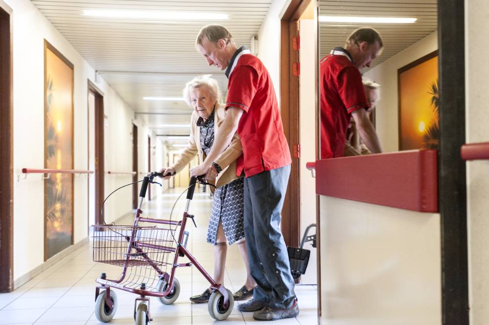 Kinesitjerapie aan oudere dame op de gang