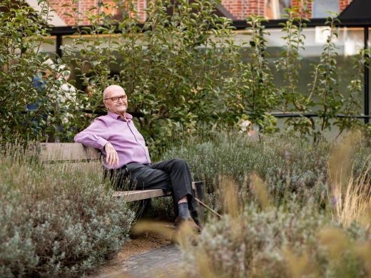 Senior man geniet van de zon pp een bankje op het binnenplein van de Refuge Gent