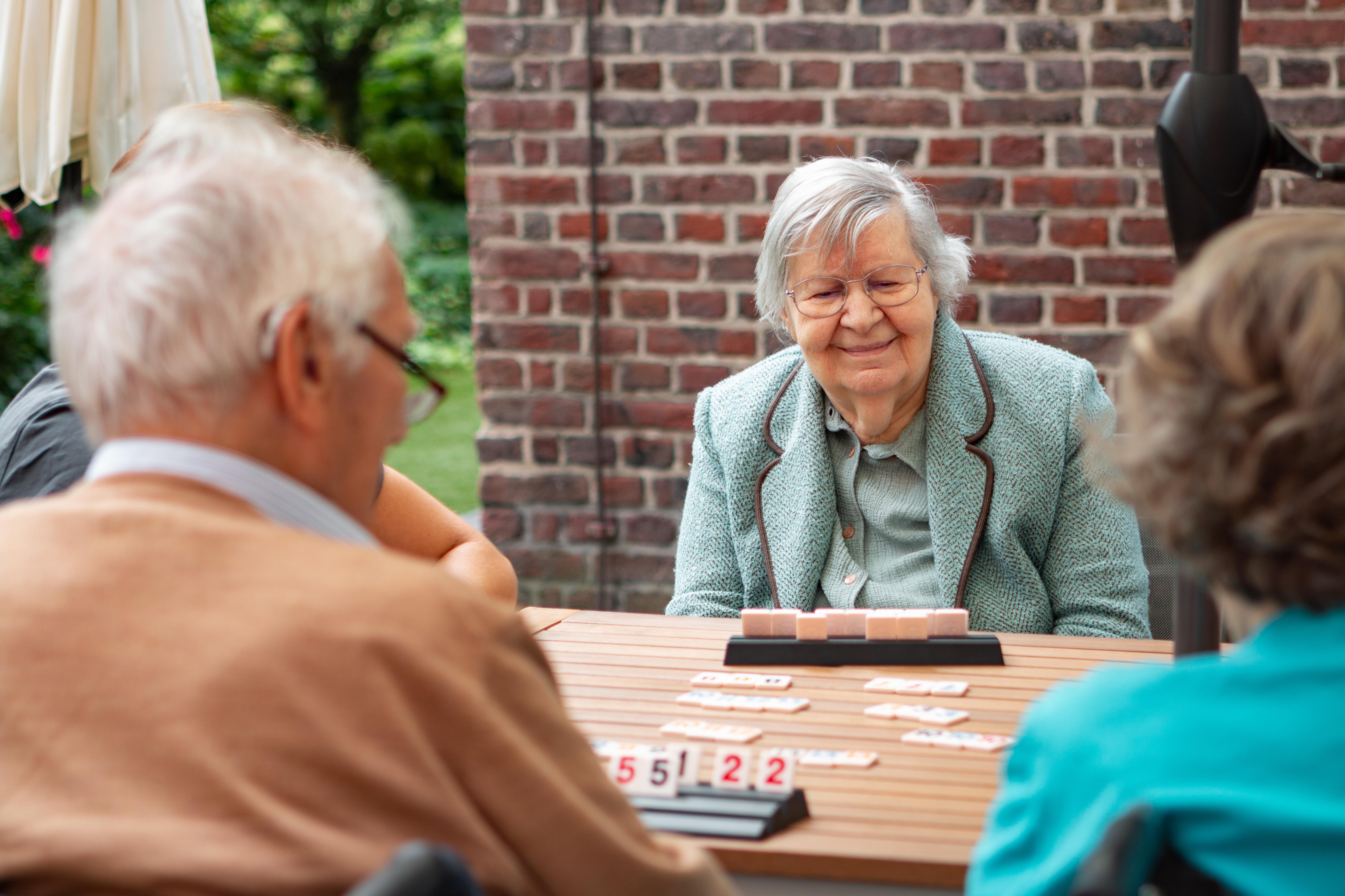 Bewoners spelen een spel op het buitenterras achter de kapel van de Refuge in Gent