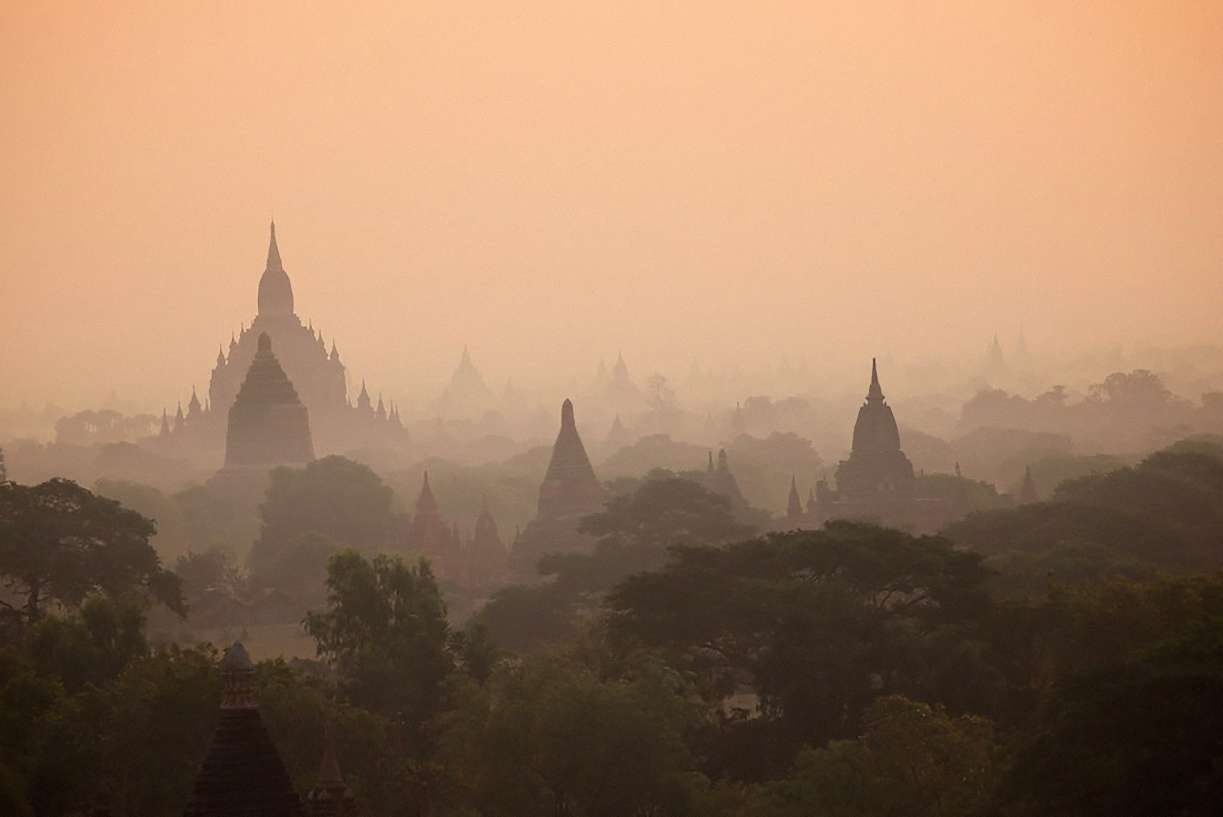 Blik op meerdere gebedshuizen in de oranje gloed van mist