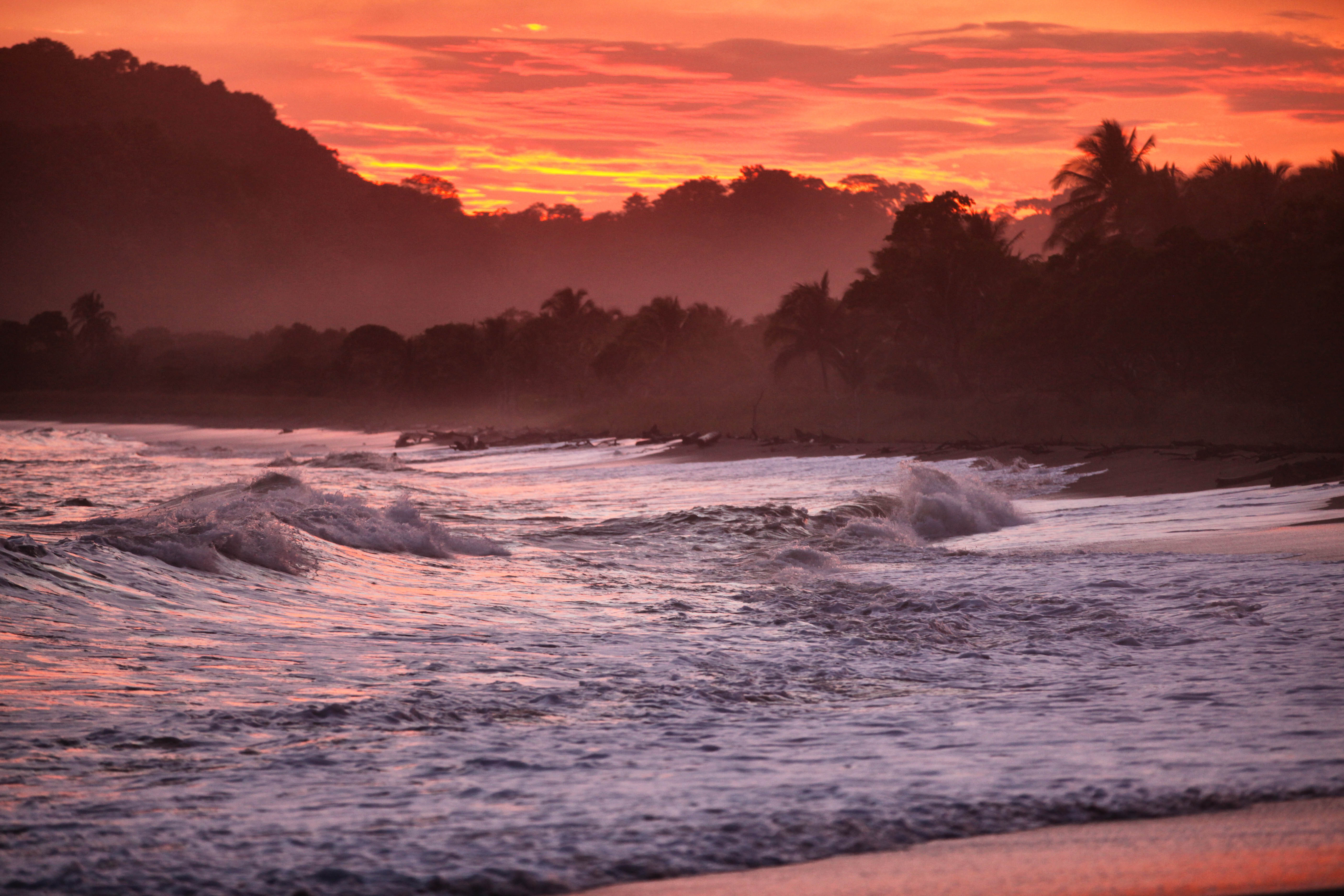 Ruige zee met schuime golven met een rode lucht bij zonsondergang