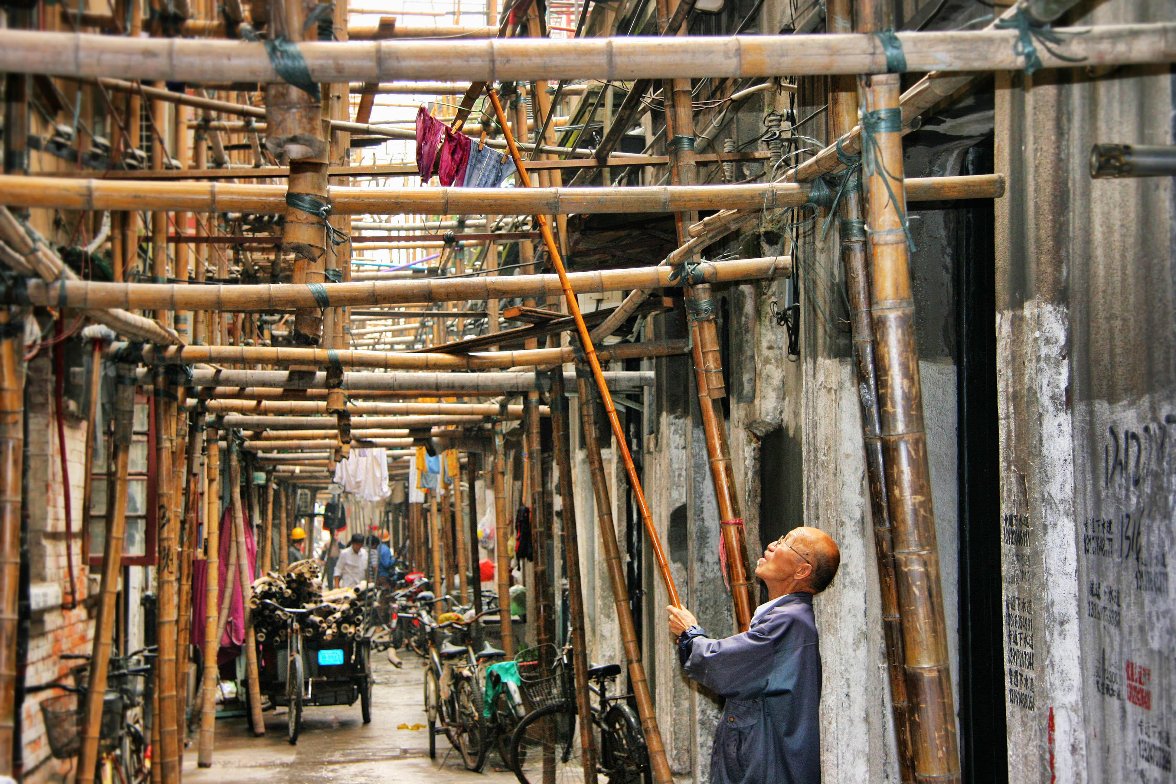 Man in steegje met bamboe constructie